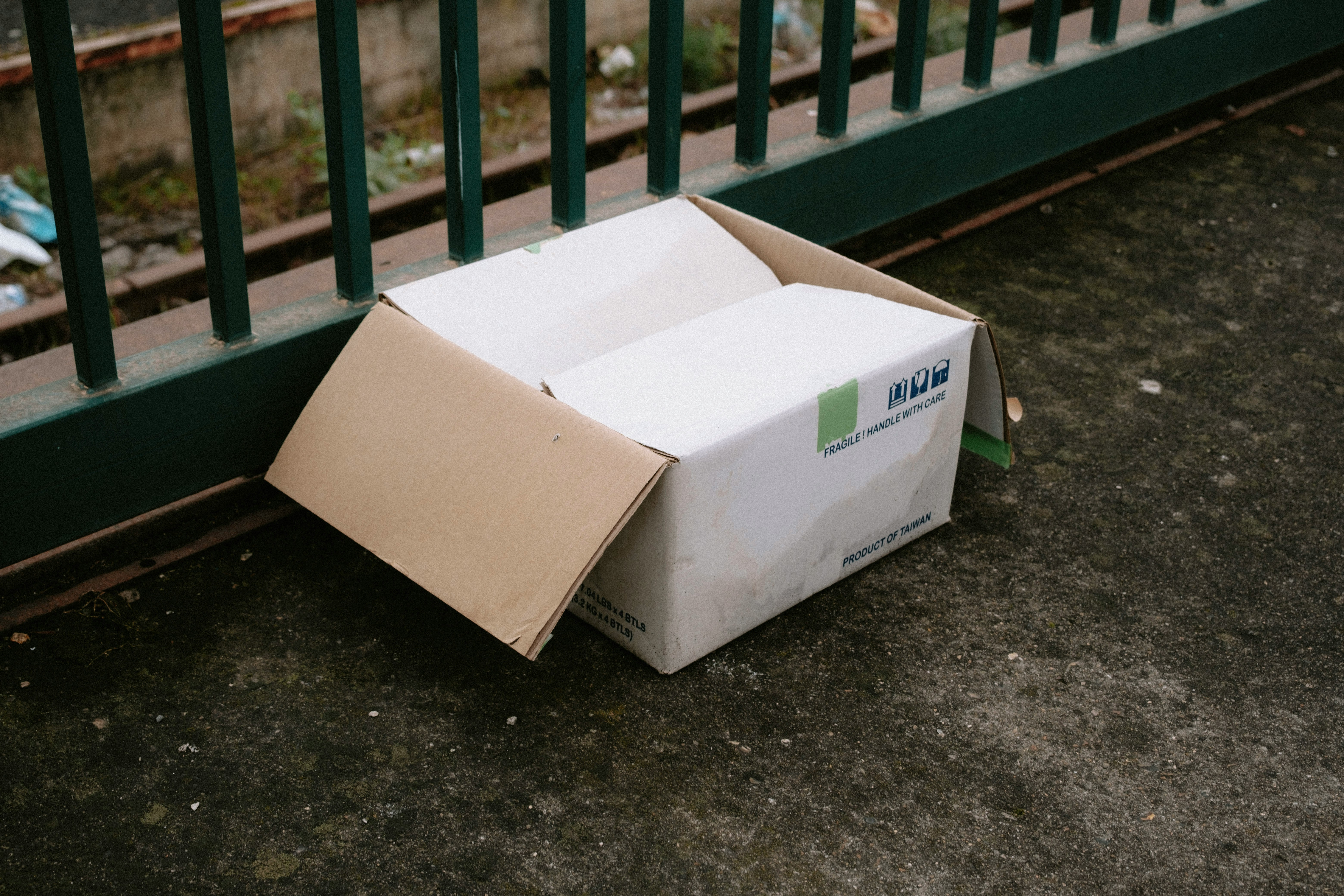 Discarded open shipping box beside a rail platform