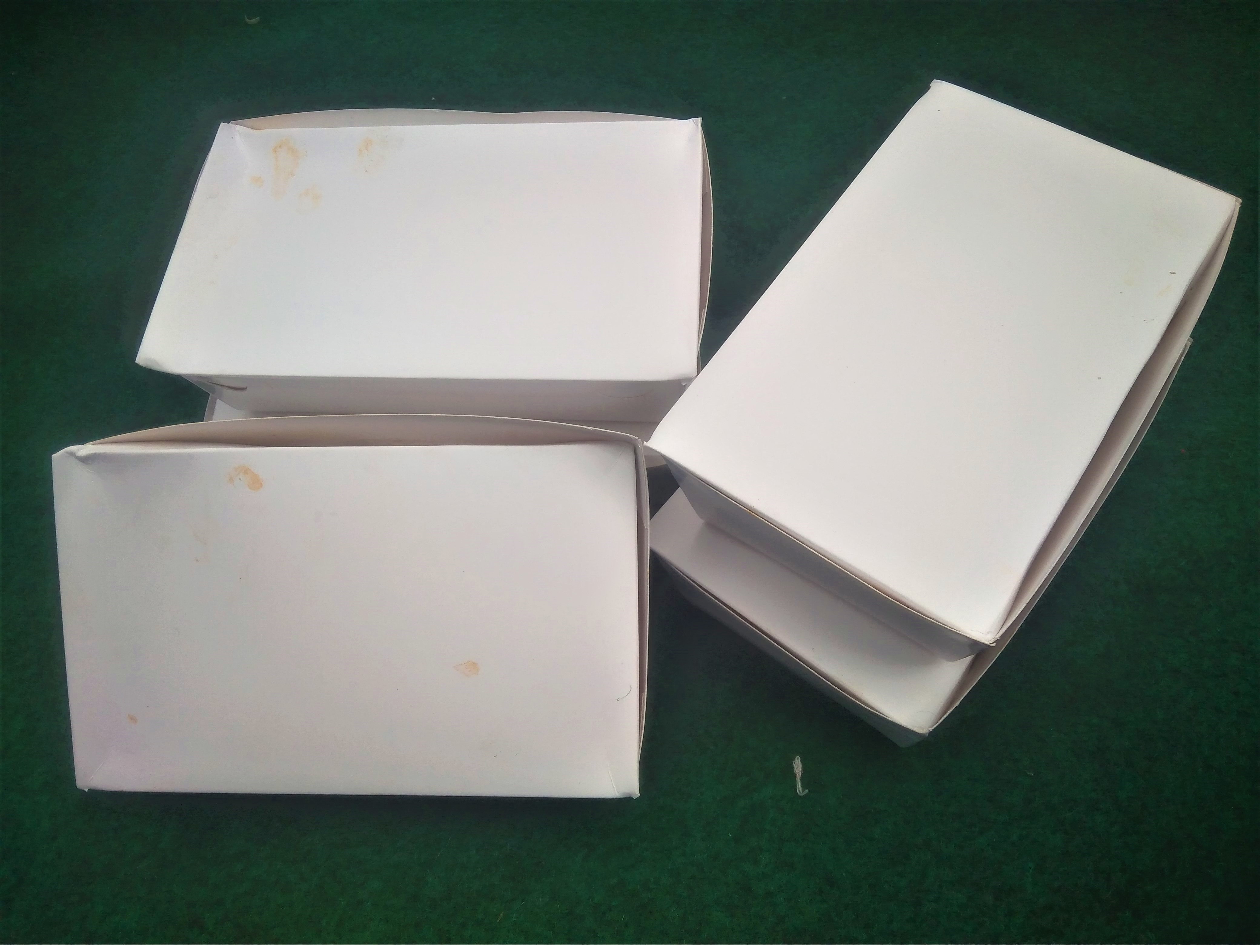 Used white paperboard food cartons on a dark green surface